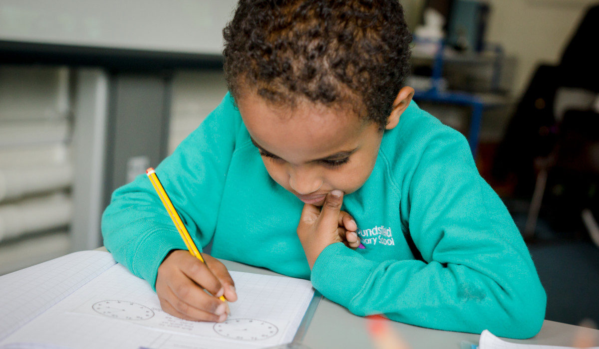 EAL Learners | A picture of a young boy writing at a desk in a school classroom