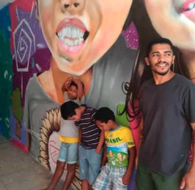 A photo of a man with some children resting on a wall with graffiti on it